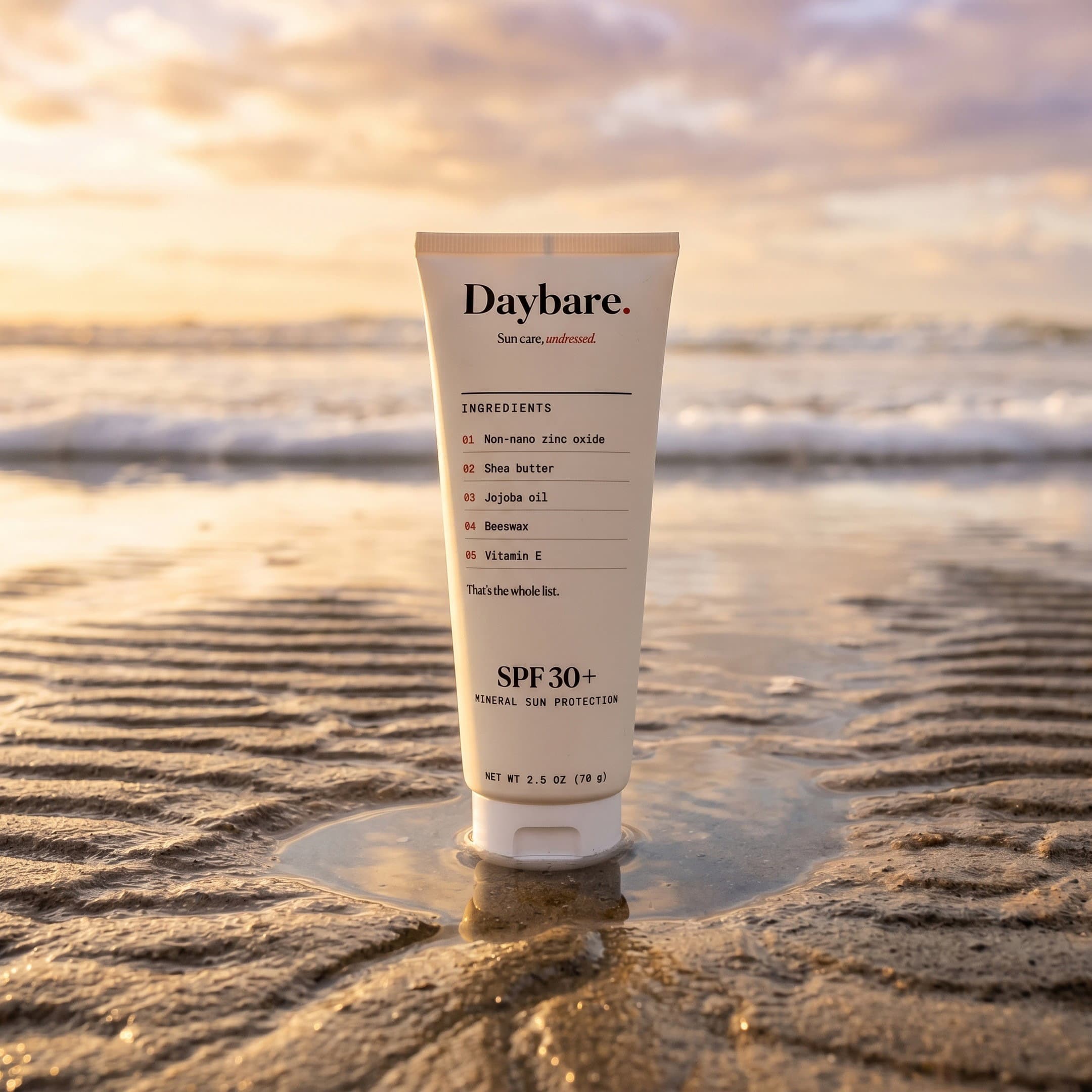 The Daybare tube standing upright in wet sand at low tide, golden-hour light on the water